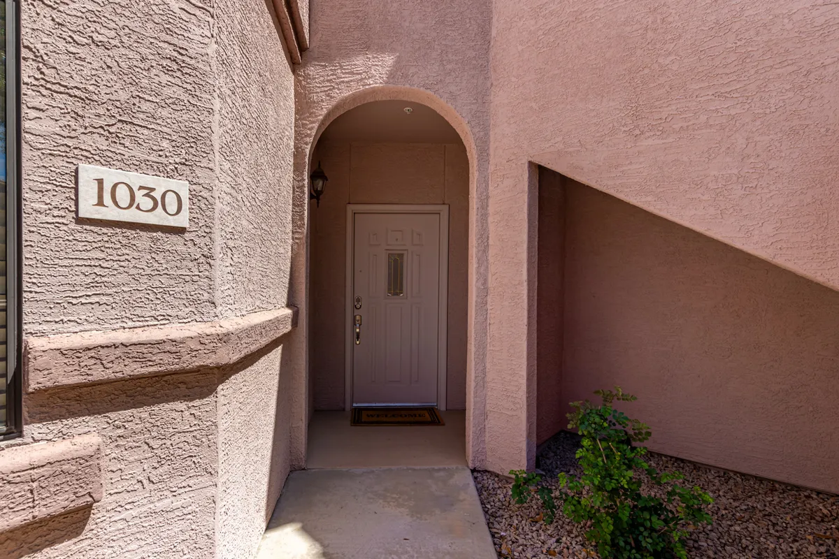 The image showcases the apartment's arched front entrance and house number, establishing a sense of arrival and belonging. The inviting doorway represents the transition from the outside into a private, comfortable sanctuary.