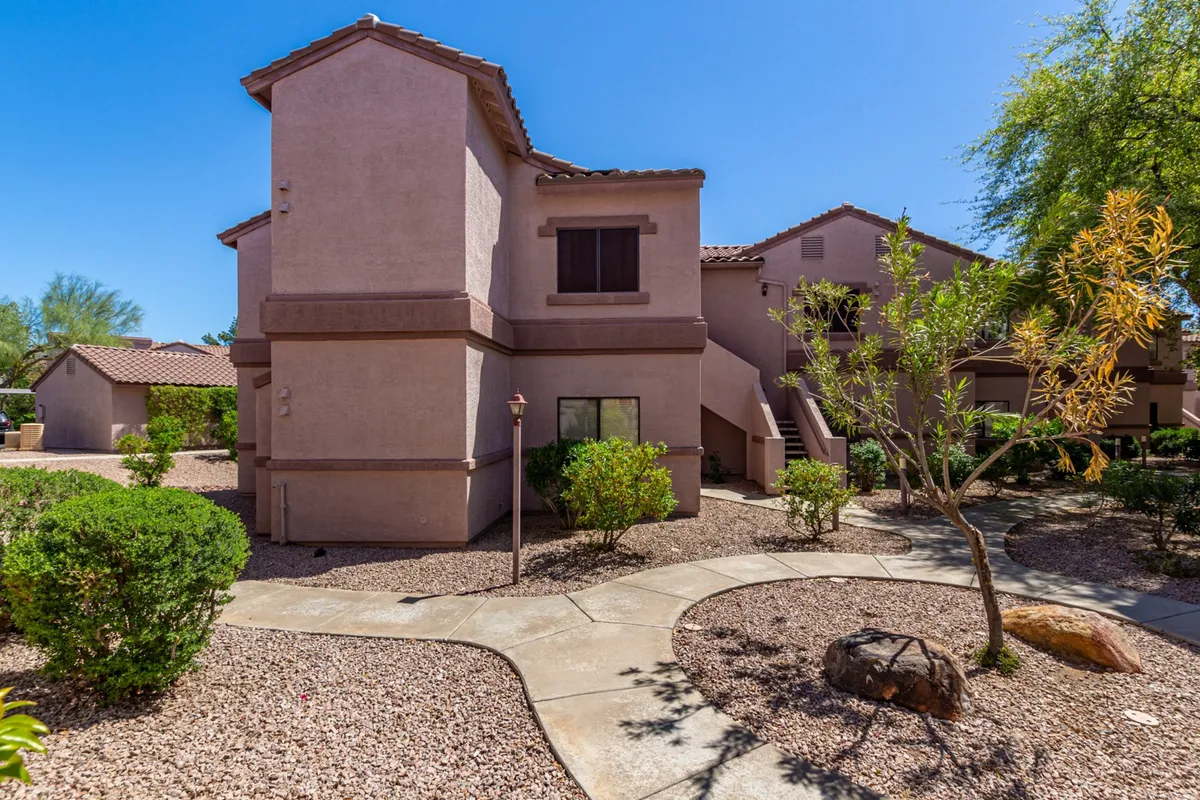 This exterior image showcases the architectural features of the property, highlighting its welcoming entrance, manicured landscaping with shrubs and rocks, and a tranquil pathway leading up to the building. The setting looks serene and private, with greenery providing a peaceful ambiance ideal for relaxation.