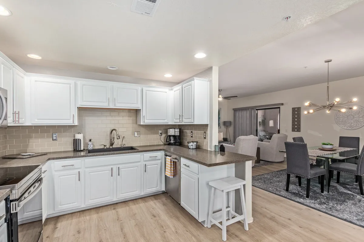 The image showcases a bright, inviting kitchen and dining area featuring white cabinetry, sleek granite countertops, stainless steel appliances, and a tastefully set dining table. The space is styled to evoke both festive gatherings and intimate meals with friends or family.