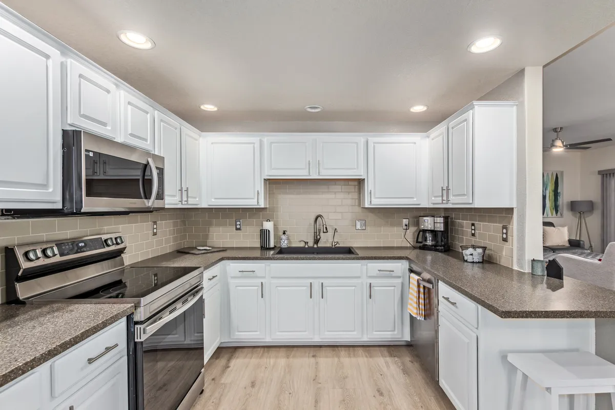 A spacious kitchen featuring a large island, gleaming stainless steel appliances, white cabinetry, and extensive countertop space. The setting feels both modern and inviting, perfect for preparing meals and entertaining family or friends.