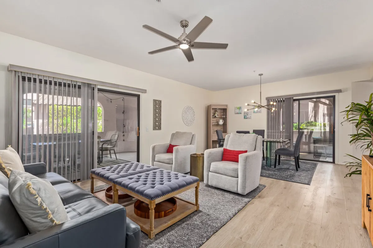 A stylish open-plan living area featuring a plush sofa, contemporary coffee table, and sliding glass doors that let in an abundance of natural light. The room is bathed in soft sunlight, creating a warm and welcoming ambiance, with ample space for relaxing or socializing.